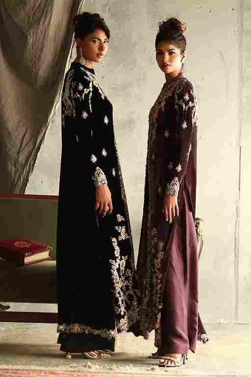 Two women wearing long, dark-colored dresses with floral patterns against a neutral background.
