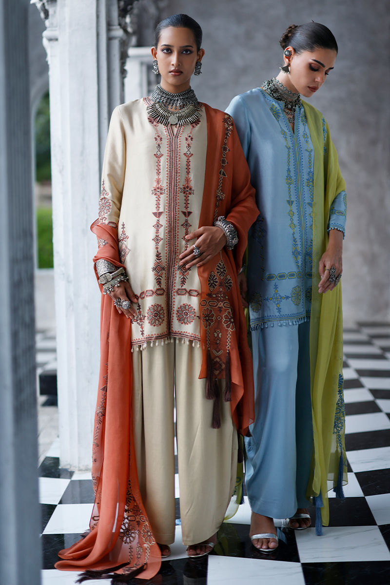 Two women in traditional outfits standing on a checkered floor.
