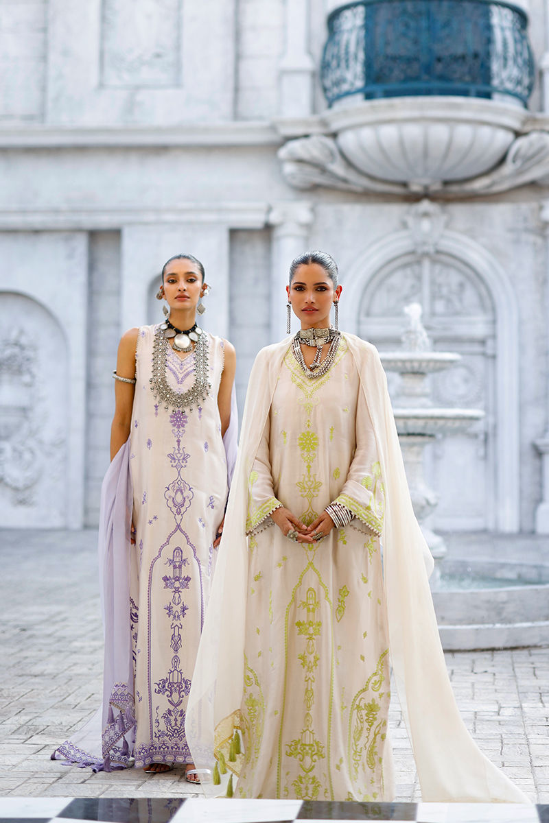 Two women in elegant dresses standing in front of a classical building.