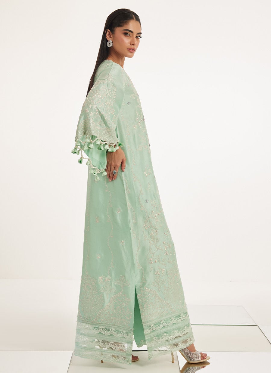 Woman wearing a light green traditional outfit with floral patterns on a white background