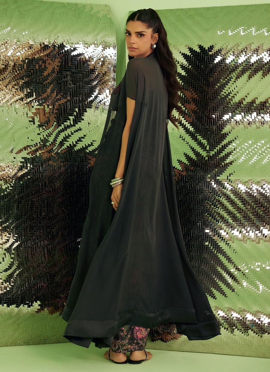 Woman in a long black dress standing against a green and silver sequin backdrop
