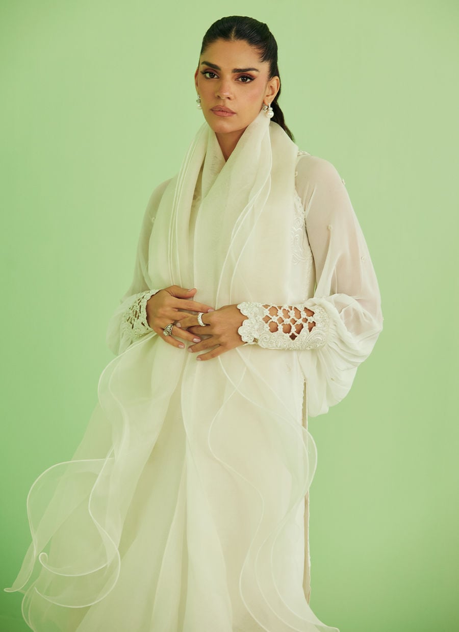 Woman wearing a white scarf and outfit against a light green background