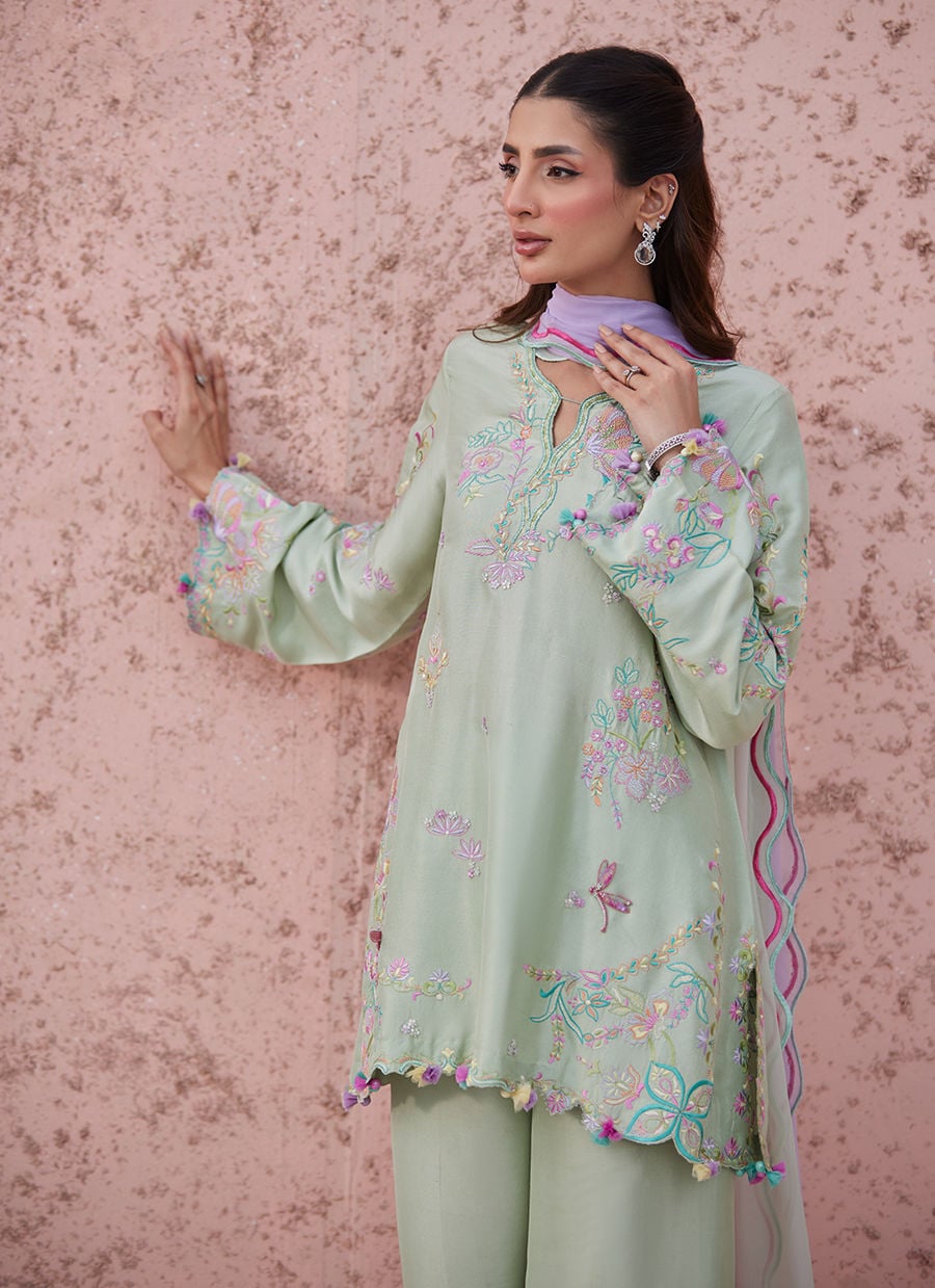 Woman wearing a light green traditional outfit with a pink and white dupatta.
