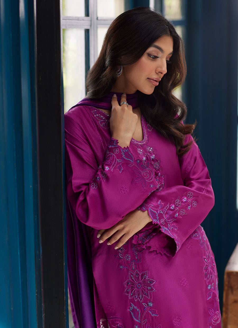 Woman wearing a vibrant purple embroidered dress indoors.