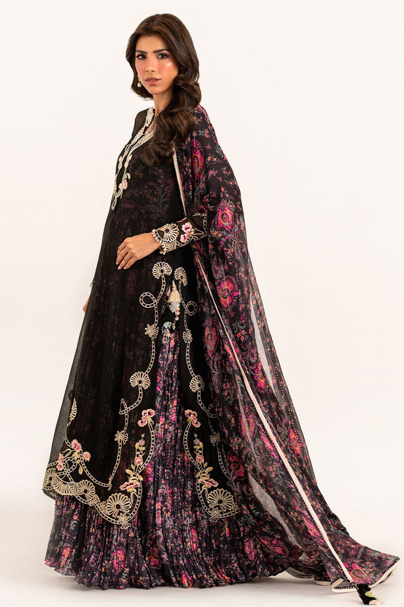 Woman wearing a black embroidered traditional outfit with a floral cape on a white background