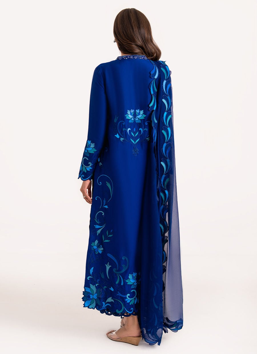 Woman wearing a blue floral embroidered dress with a matching jacket on a white background