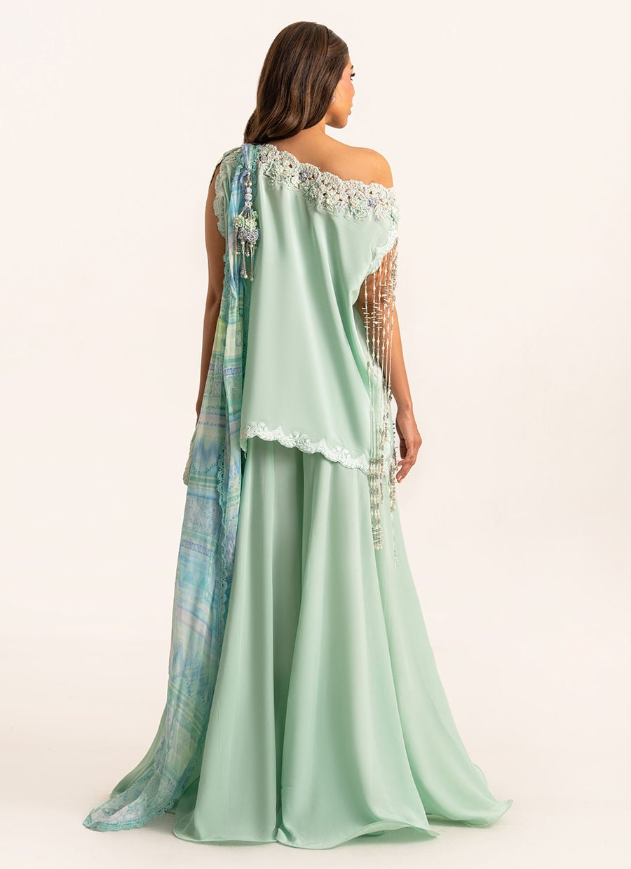 Woman wearing a light green off-shoulder dress with floral embellishments and a matching dupatta on a white background