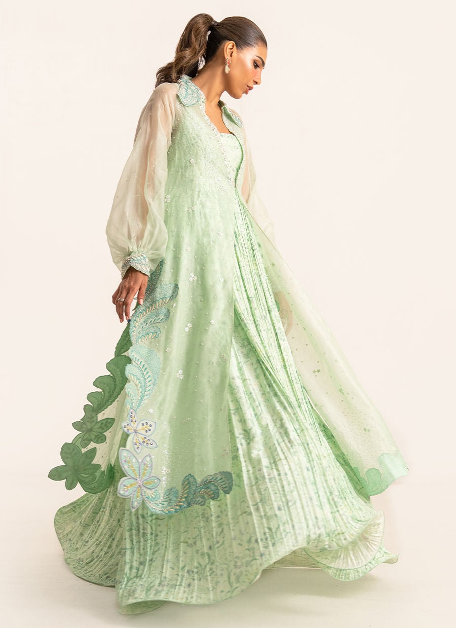 Woman wearing a light green embroidered dress on a white background