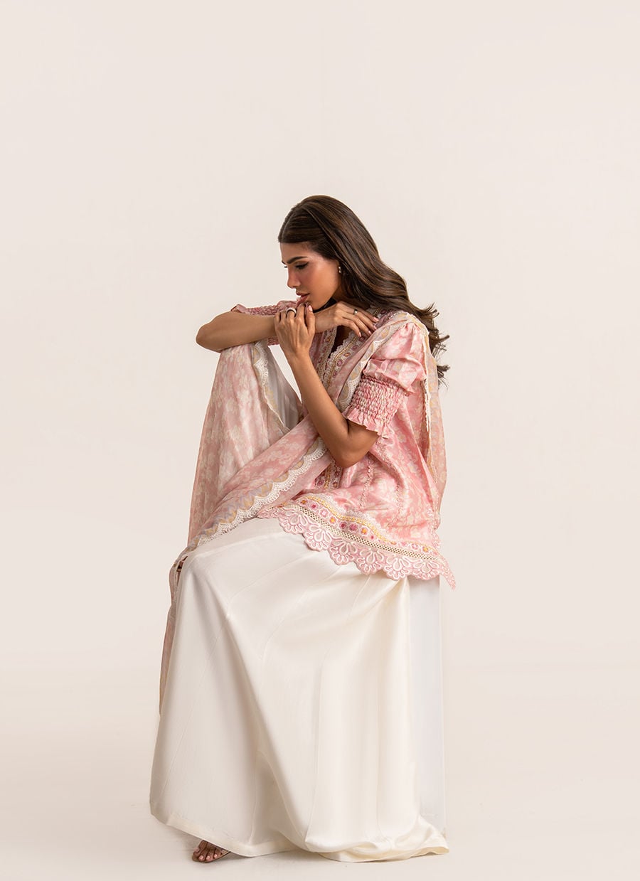 Woman wearing a traditional outfit with a pink dupatta on a white background