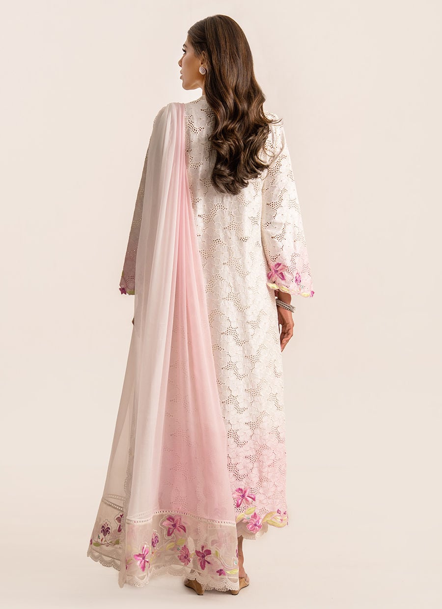 Woman wearing a white embroidered outfit with pink dupatta on a beige background