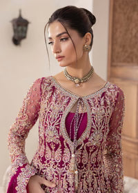 Woman wearing a pink and gold embroidered traditional outfit with jewelry.