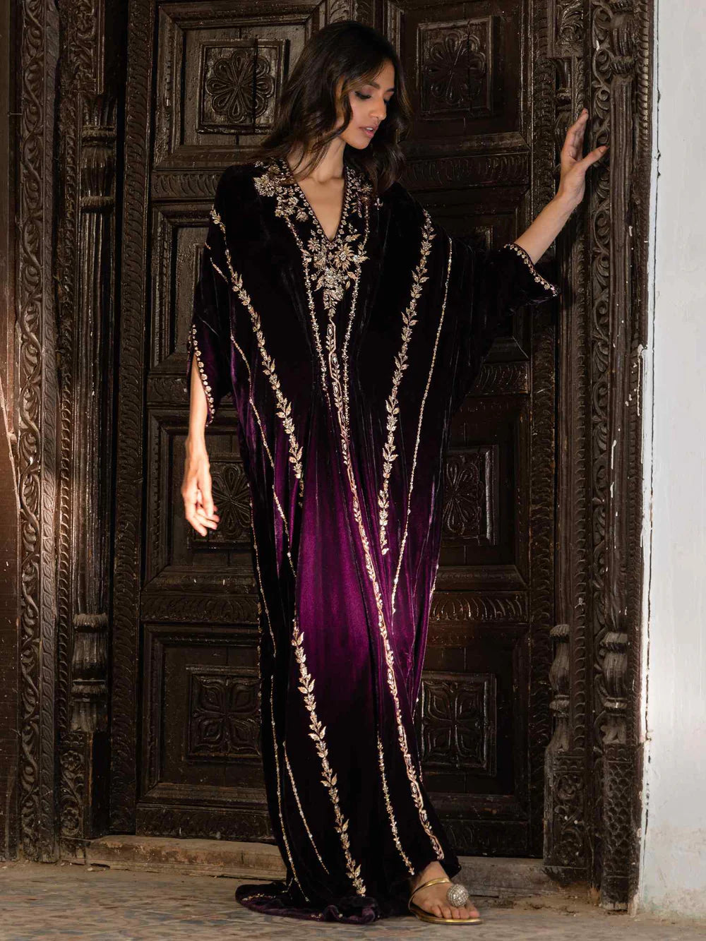 Woman wearing a black and purple dress with gold accents in an ornate setting