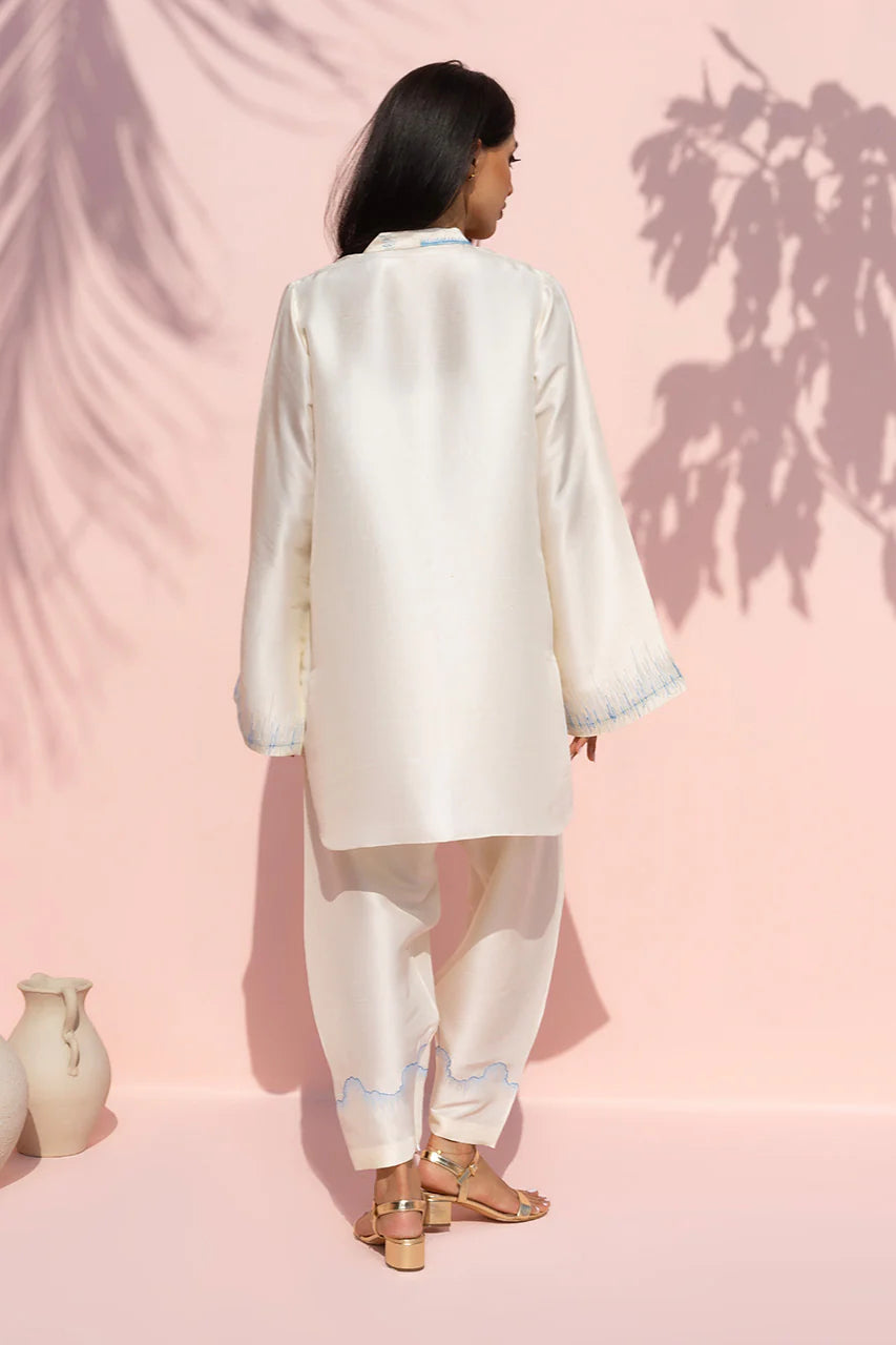 Person wearing a white satin outfit against a pink background