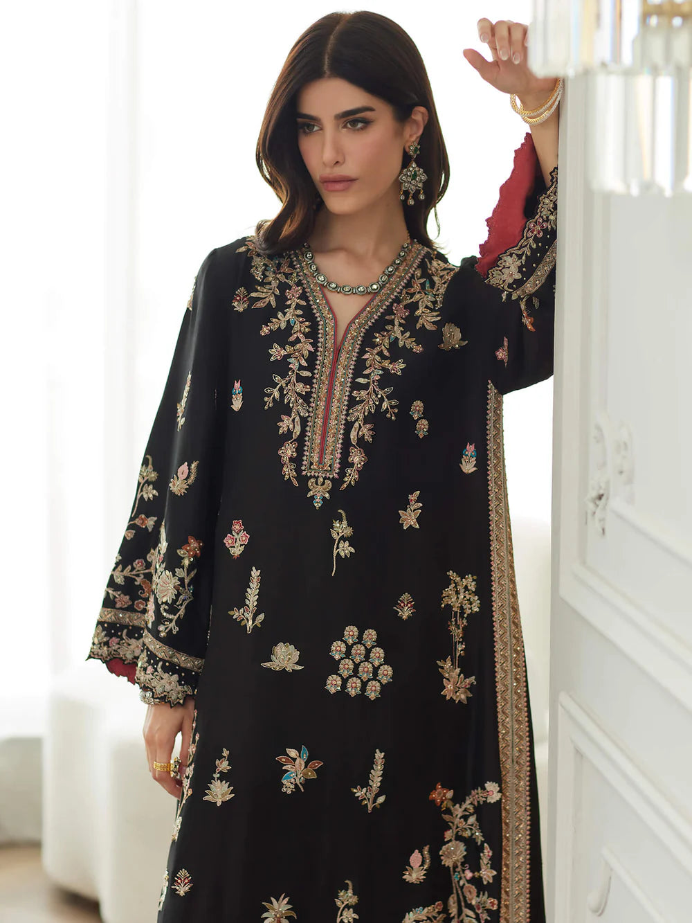 Woman wearing a black embroidered dress in an indoor setting