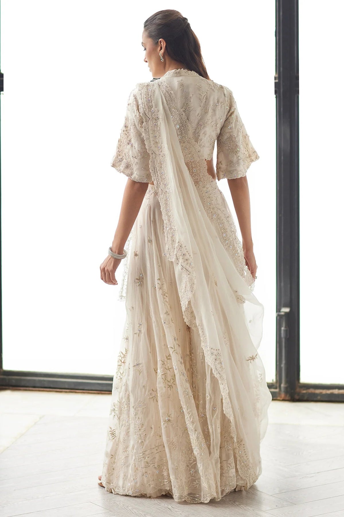 Woman wearing a beige embroidered saree in a minimal indoor setting