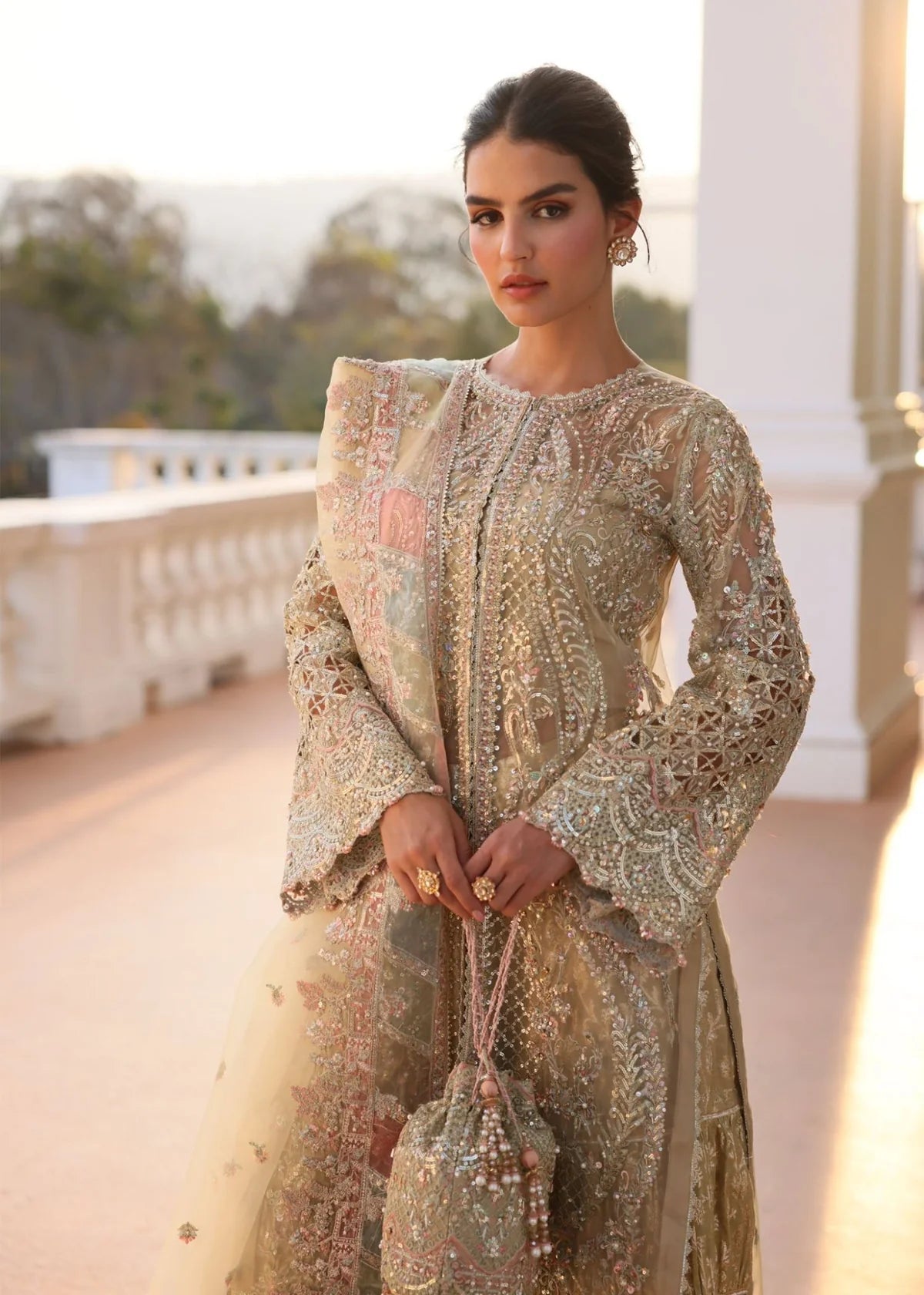 Woman wearing a traditional embroidered outfit on a balcony with a scenic background