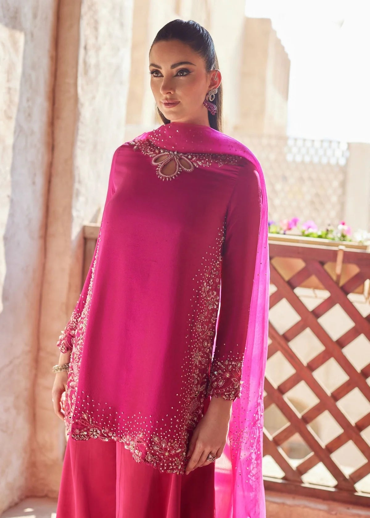 Woman wearing a pink traditional outfit with intricate designs in a bright setting
