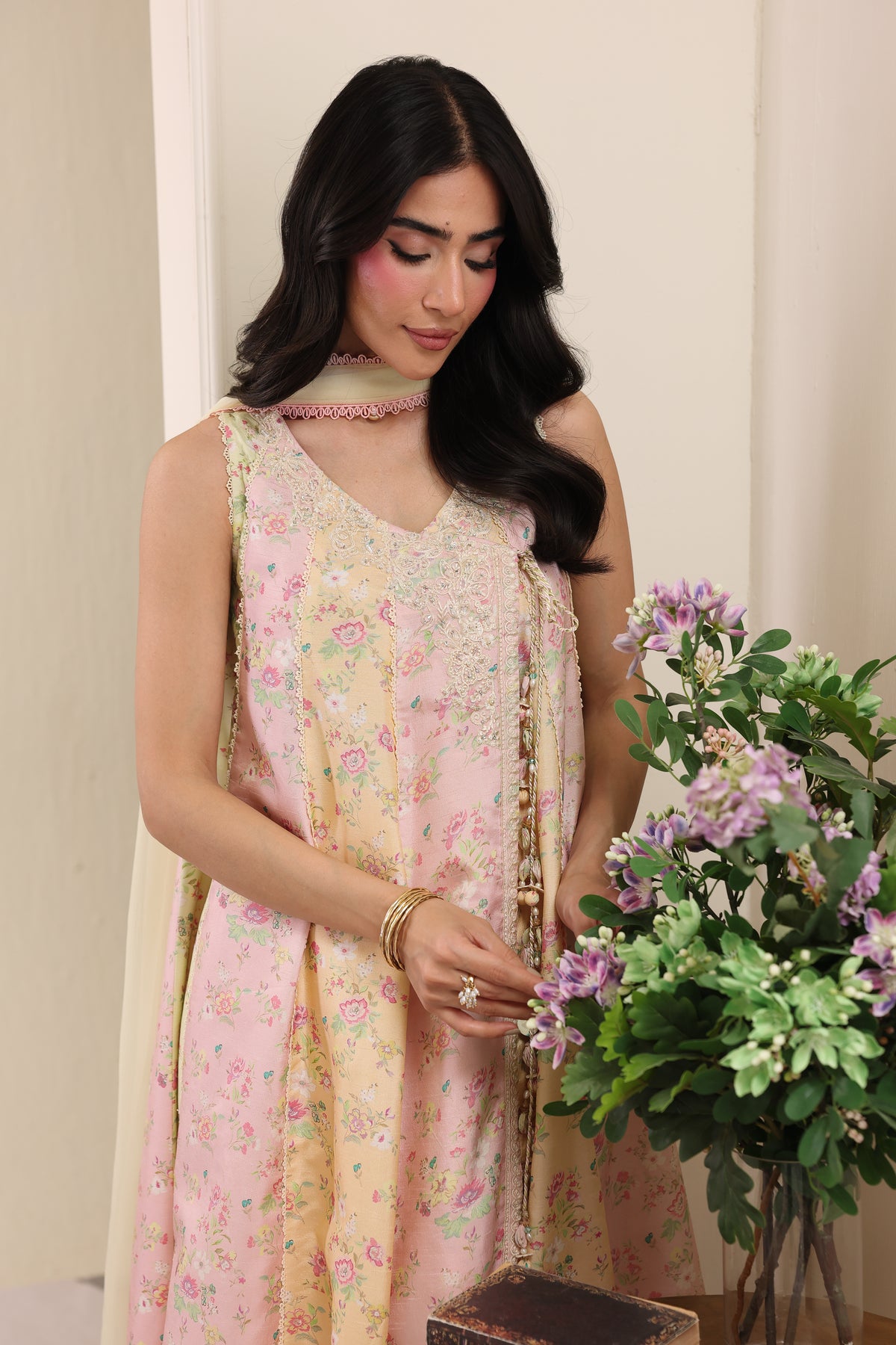 Woman in a floral dress holding a bouquet of flowers indoors.