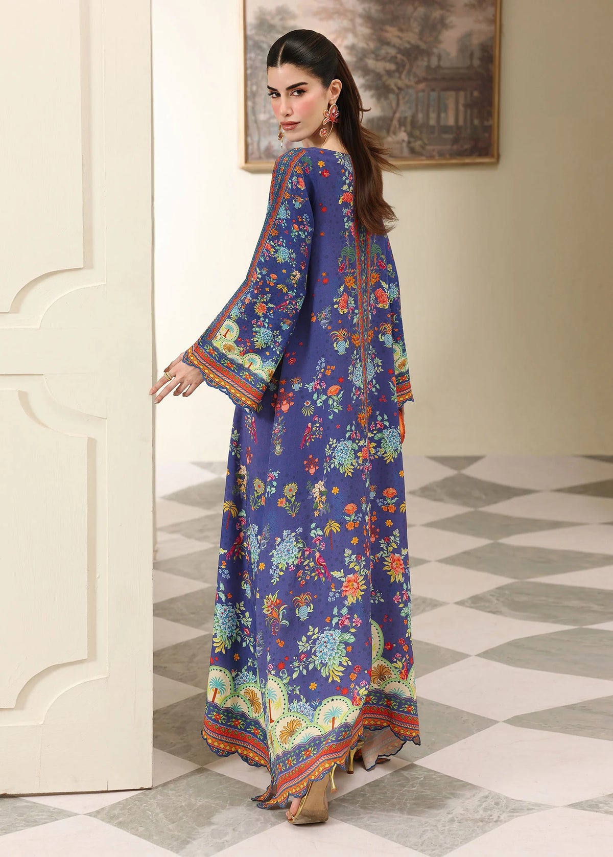Woman in a colorful floral dress standing in a room with a checkered floor.