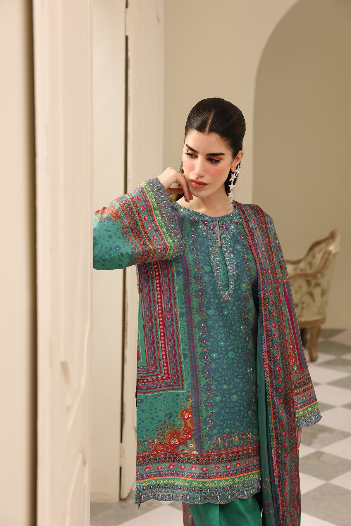 Woman wearing a traditional embroidered outfit in a decorative interior setting