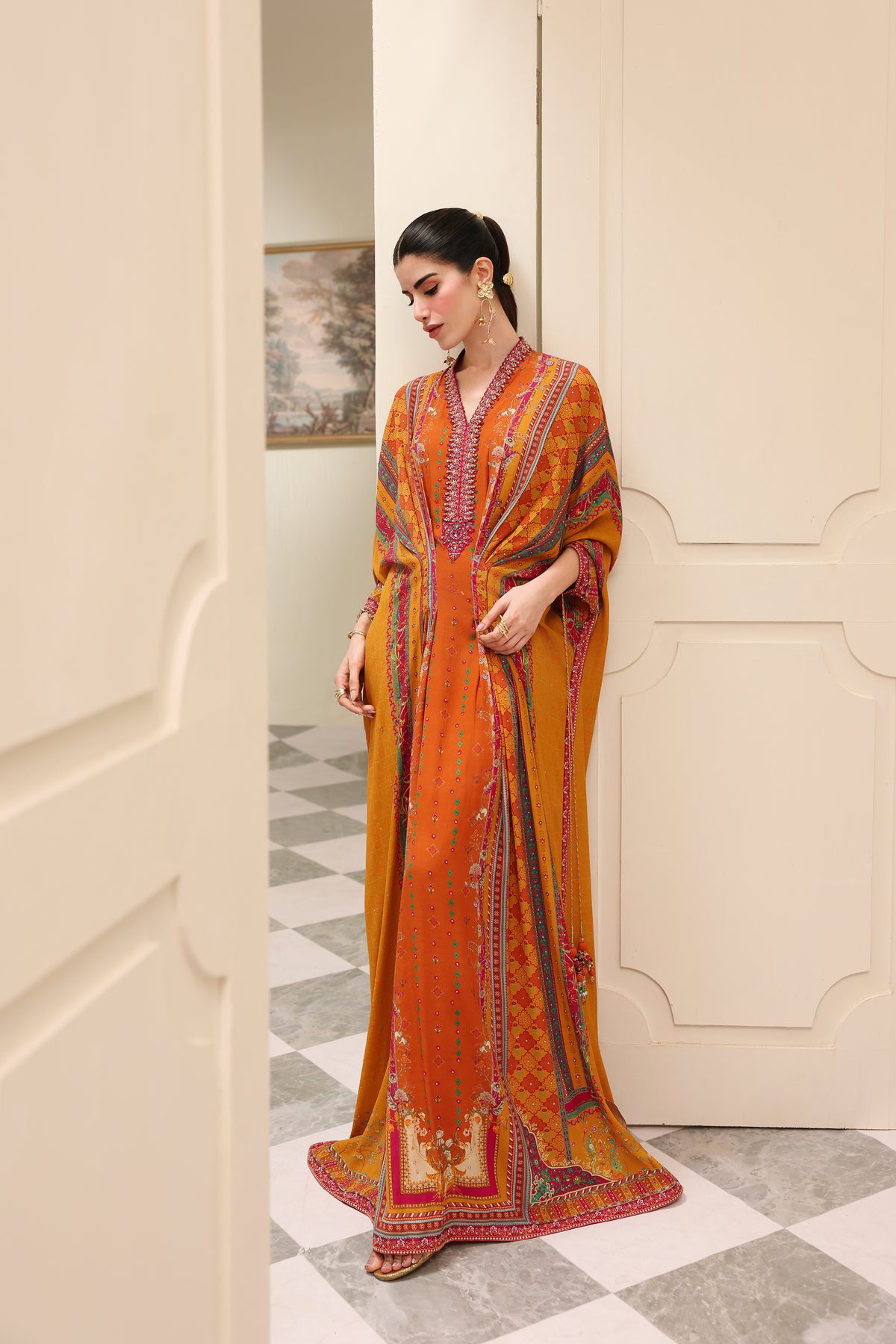 Woman in an orange patterned dress standing in a doorway.