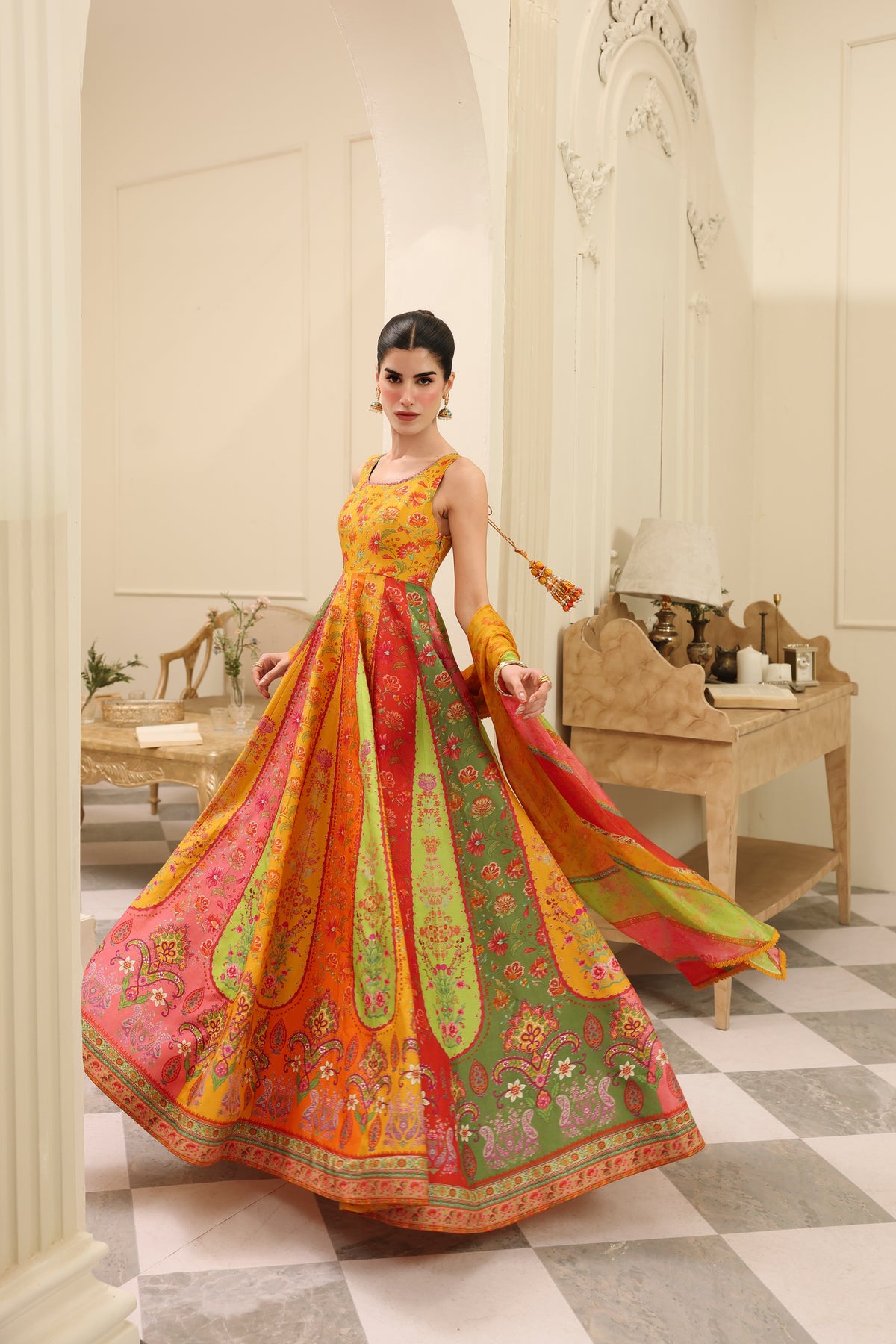 Woman in a colorful traditional dress standing in an elegant interior setting.