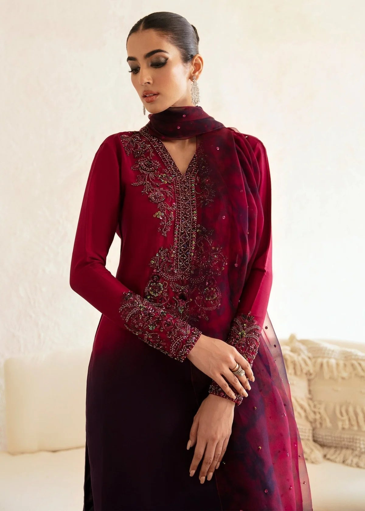 Woman wearing a burgundy embroidered dress with a neutral background