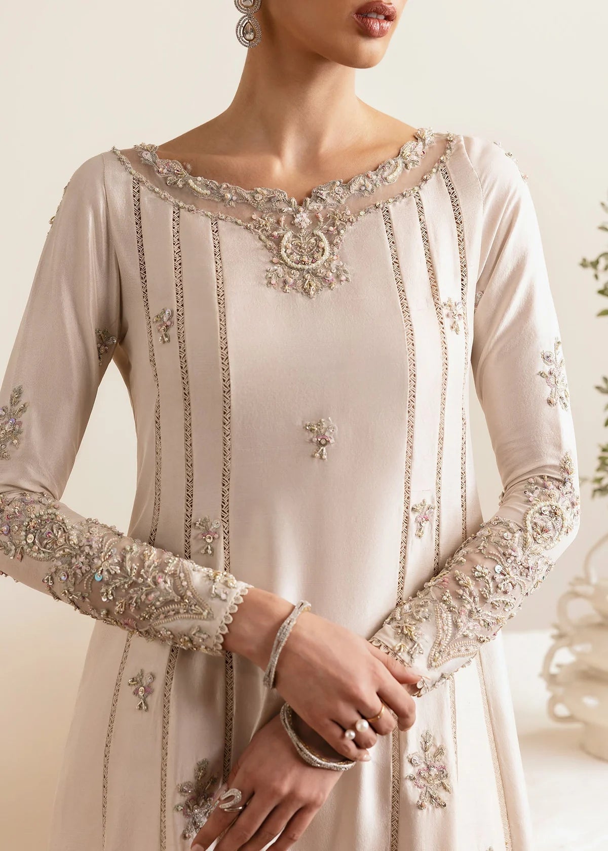 Close-up of a white embroidered dress with intricate detailing on a neutral background
