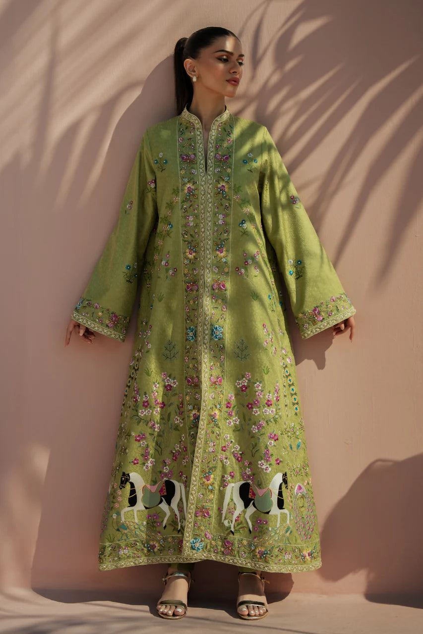 Woman wearing a green embroidered dress against a beige wall