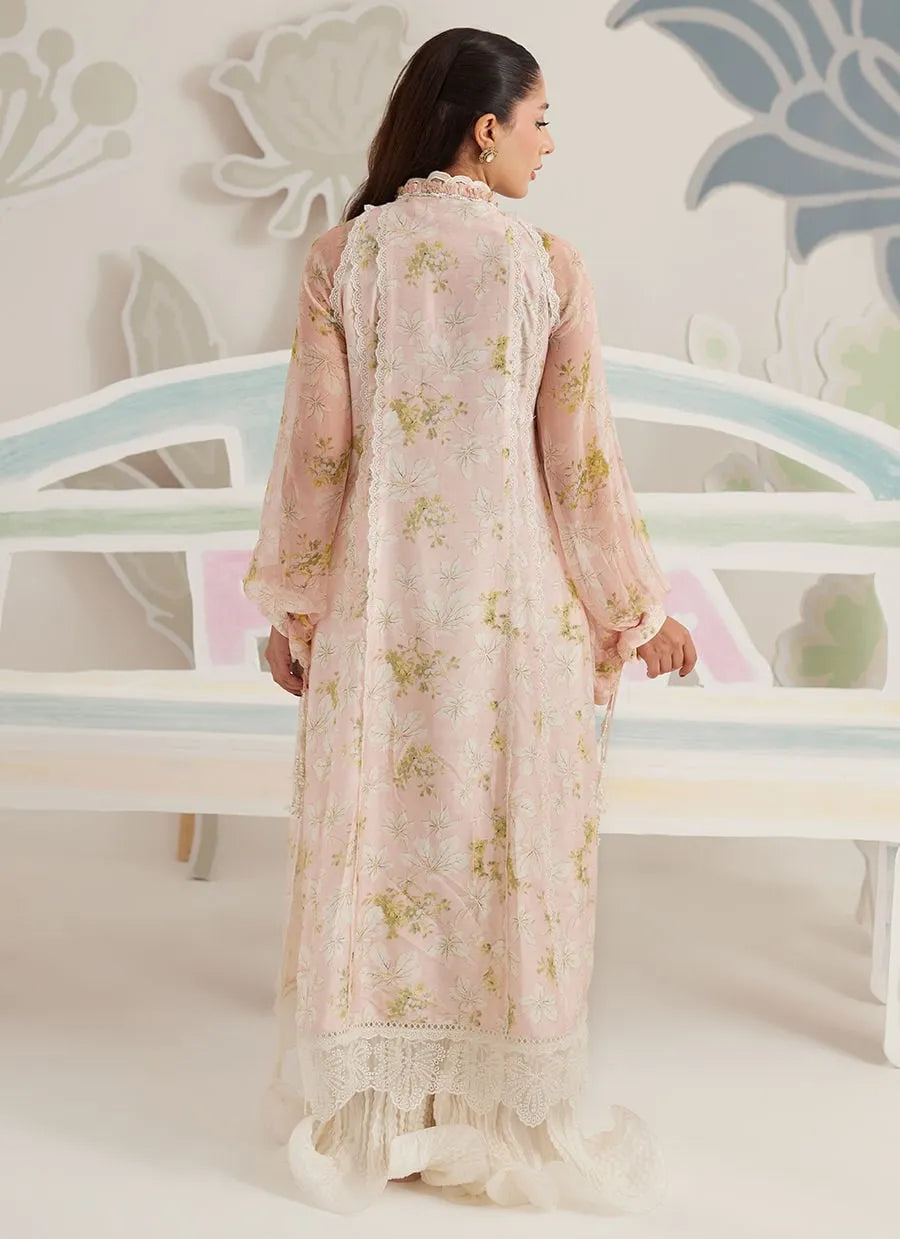 Woman wearing a light pink floral dress standing in front of a decorative wall.
