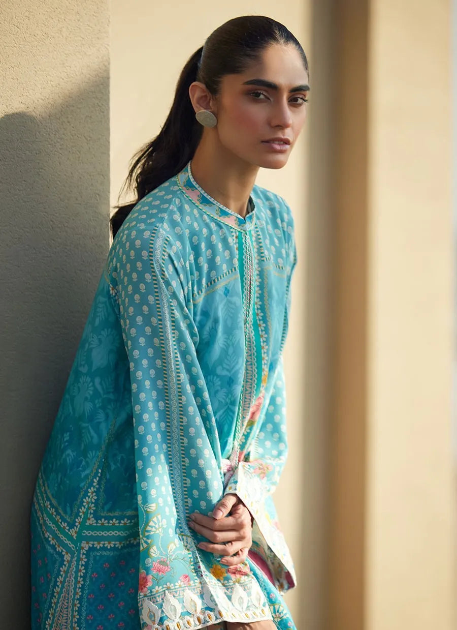 Woman wearing a blue embroidered traditional outfit against a neutral background