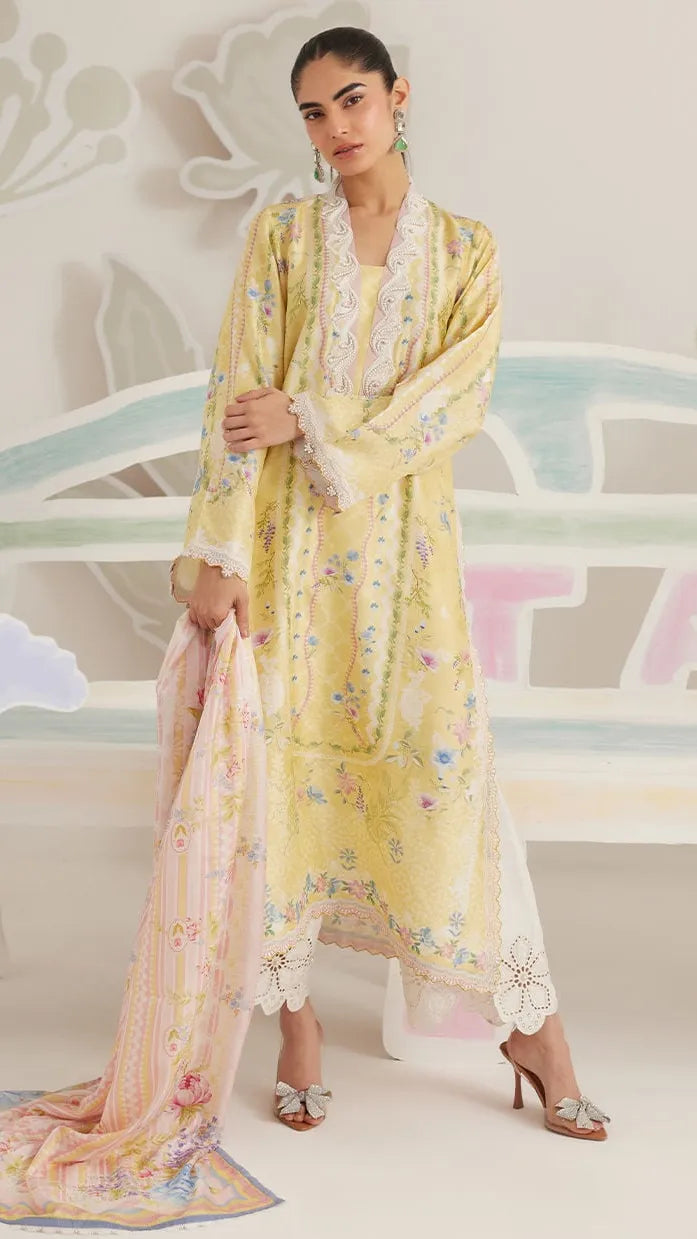 Female model posing indoors in a pastel yellow embroidered festive outfit with floral motifs, paired with a matching printed dupatta and heels.