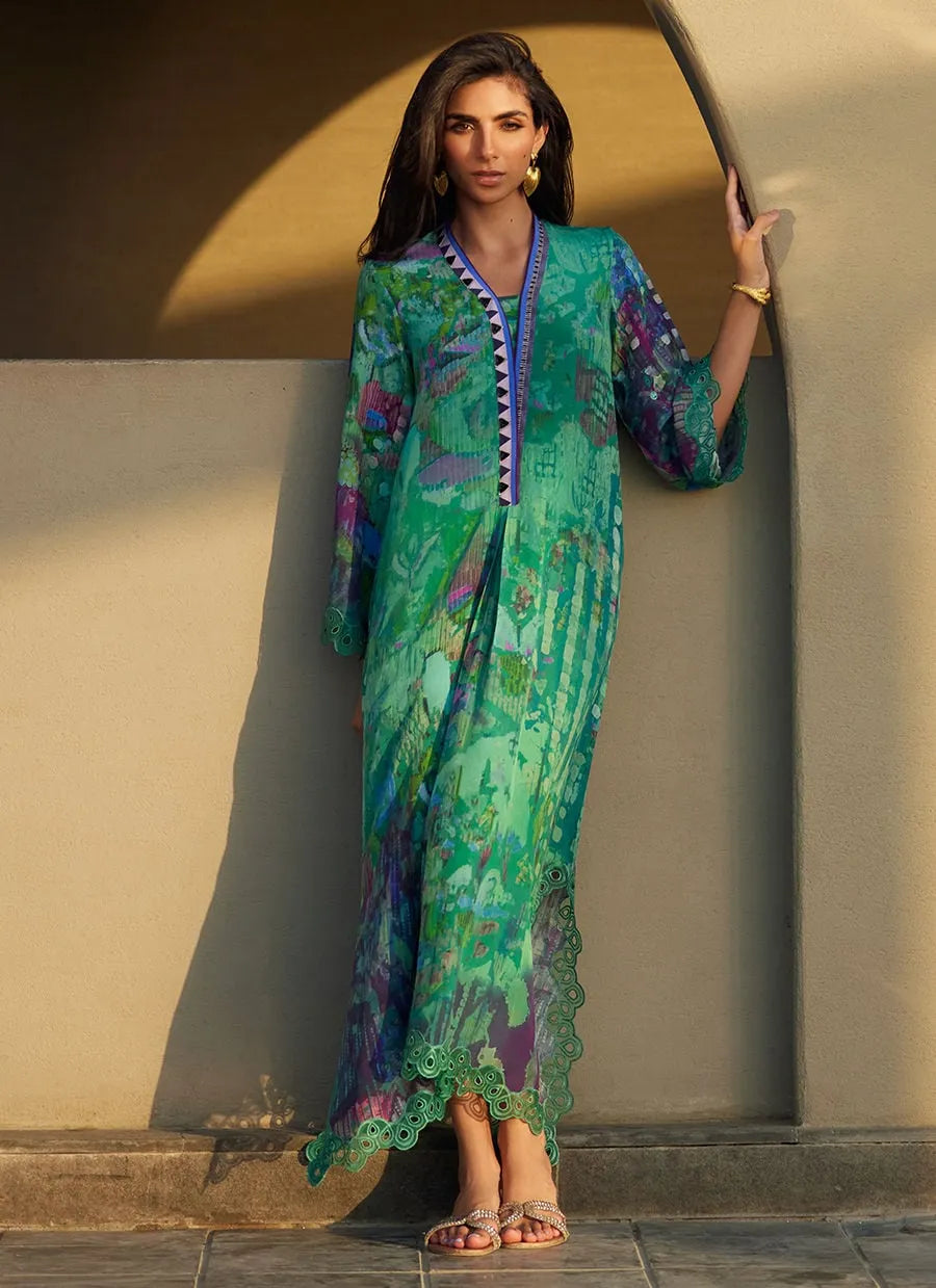 Woman wearing a colorful dress standing against a beige wall.