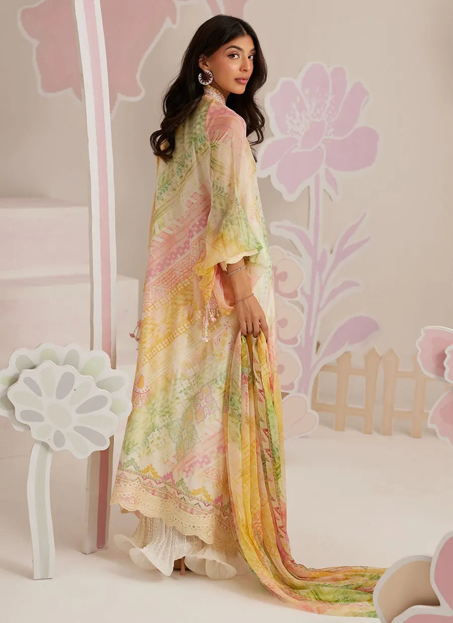 Woman wearing a colorful floral dress in a decorated room with pink flowers.