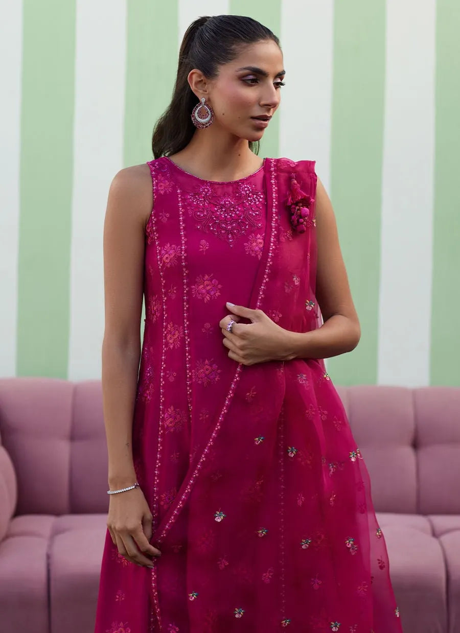 Woman wearing a pink embroidered dress with a floral detail against a striped background