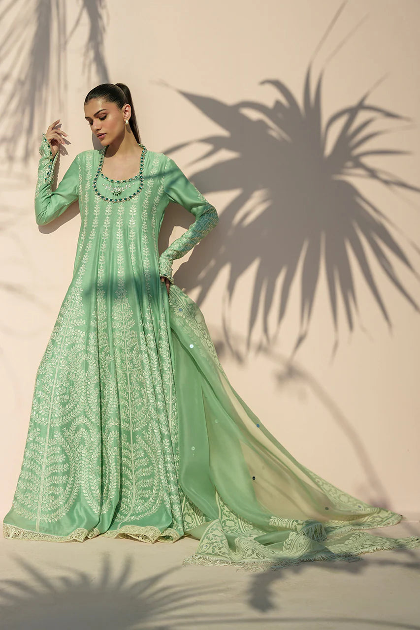 Woman wearing a green embroidered traditional outfit with a beige background