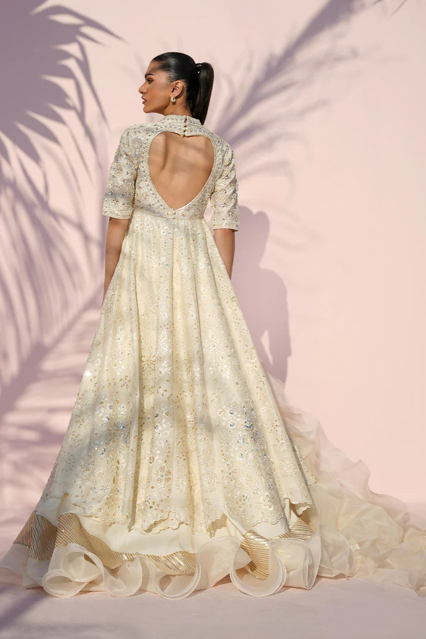 Woman wearing a cream-colored embroidered dress against a pink background
