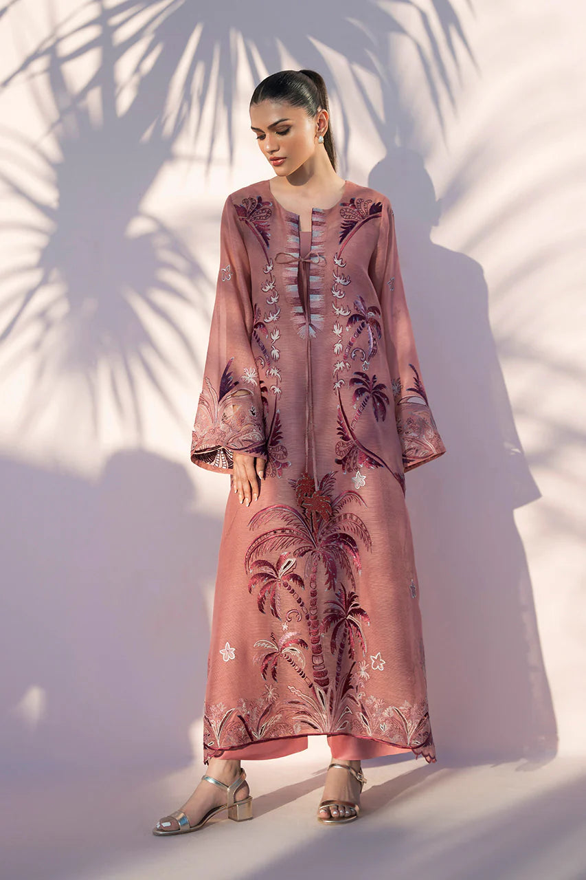 Woman wearing a long, patterned dress standing against a light background with palm leaf shadows.