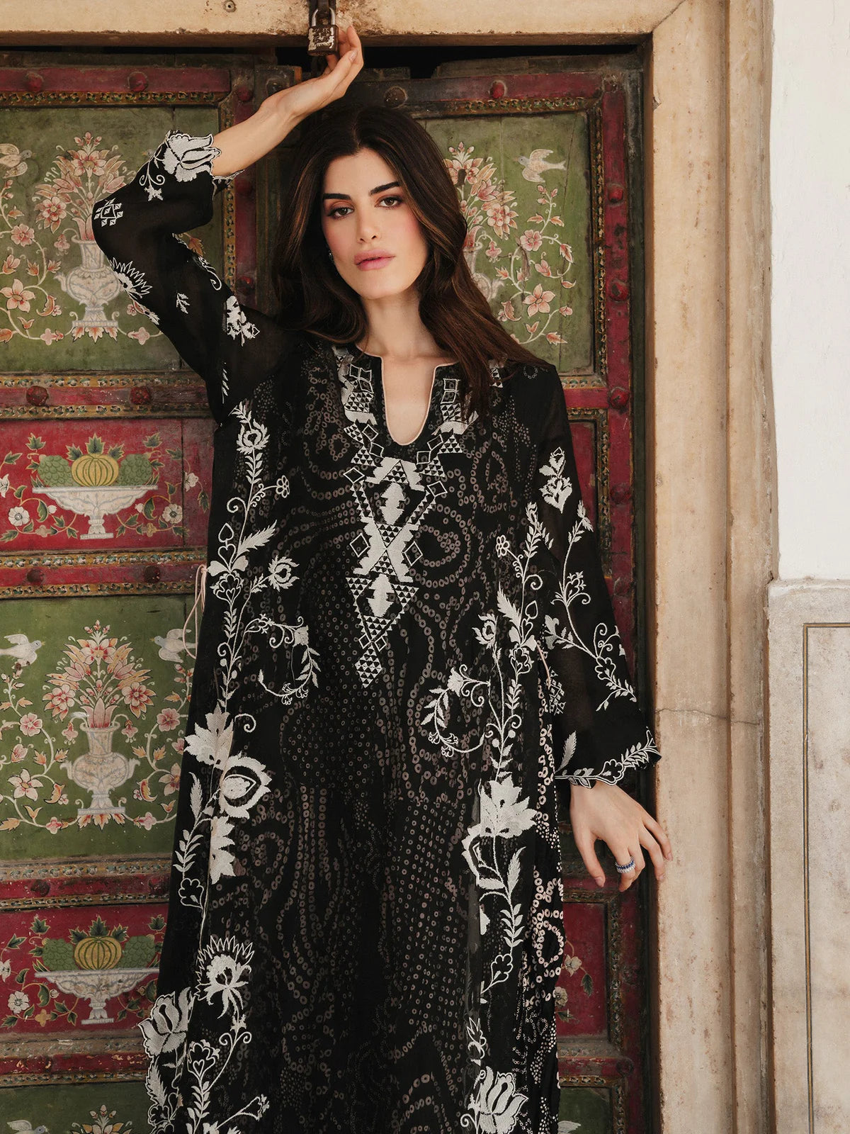 Woman wearing a black and white patterned dress standing in front of a decorative wall.