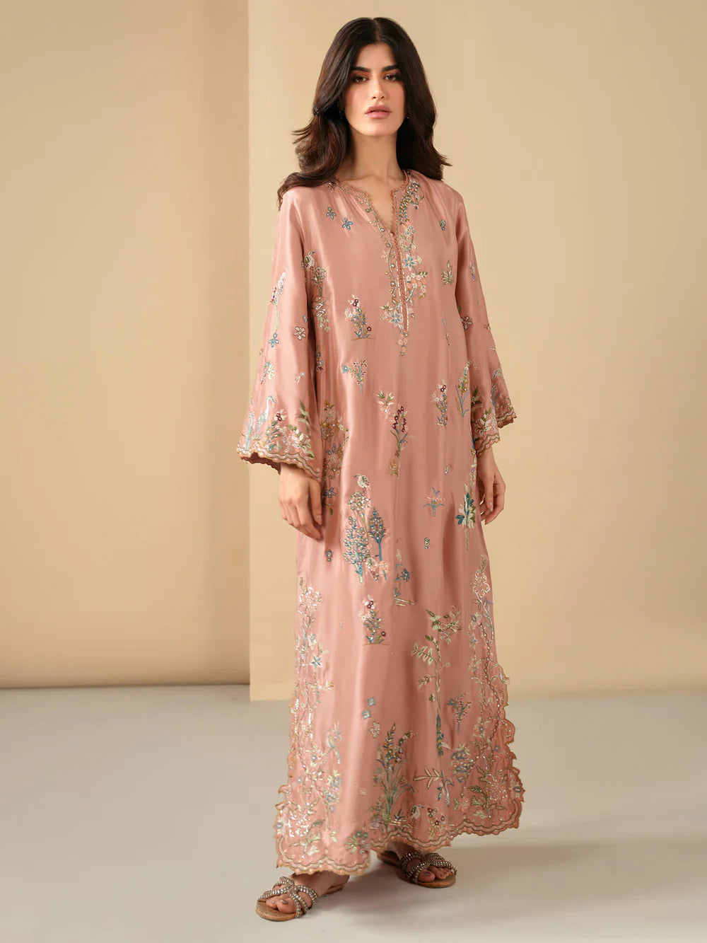 Woman wearing a pink floral dress against a beige background