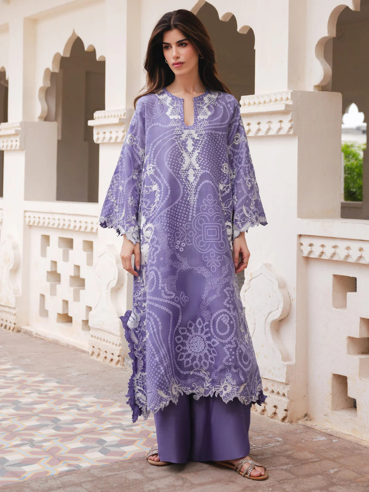 Woman wearing a purple embroidered dress standing in front of an architectural background