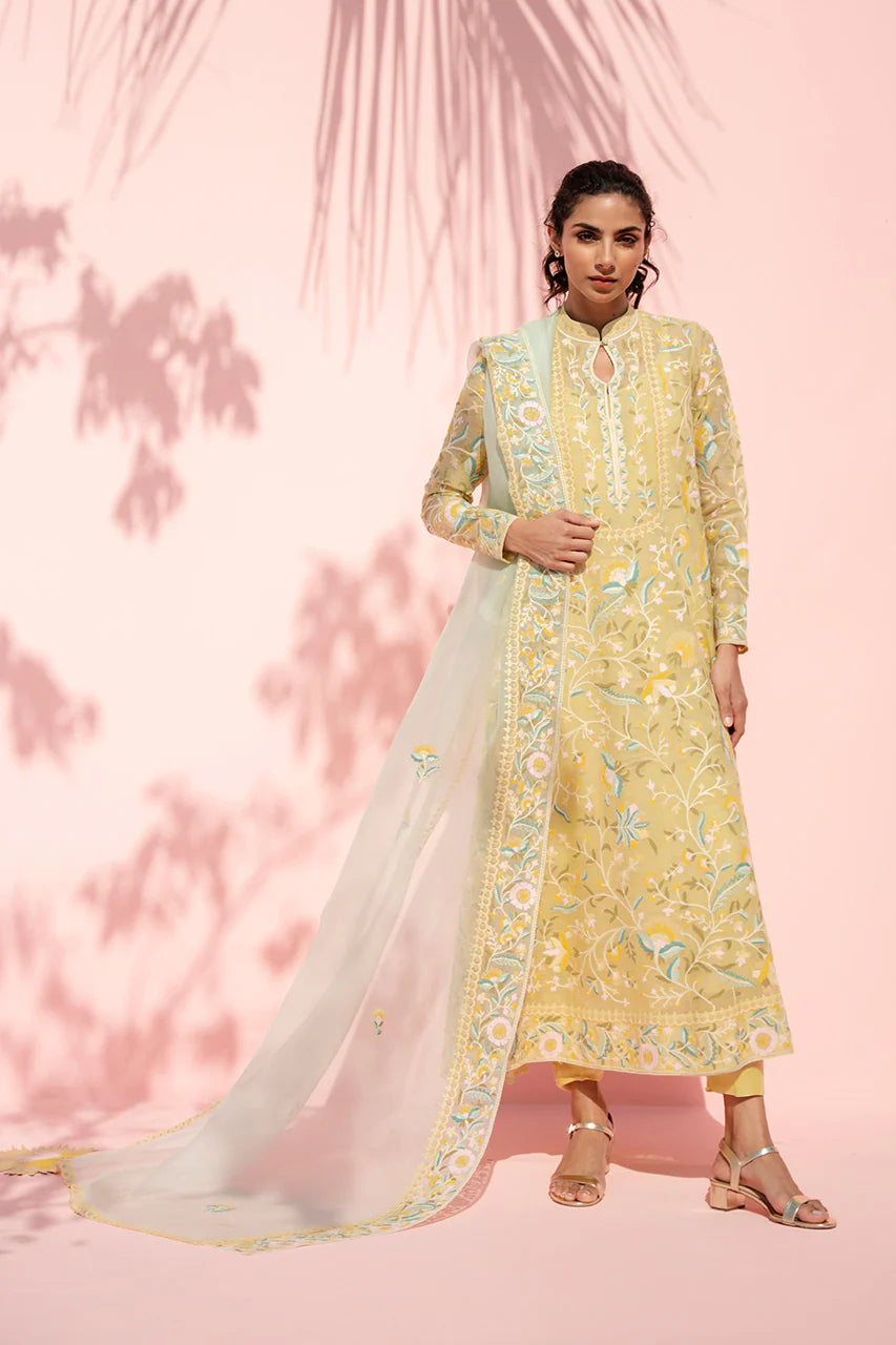 Woman wearing a yellow floral kurta with a white dupatta against a pink background