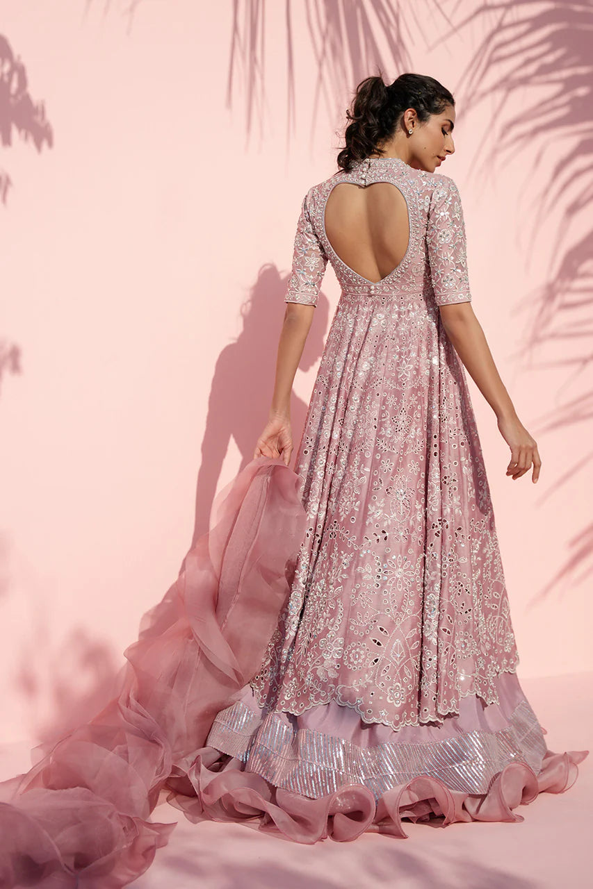 Woman in a pink embroidered gown against a pink background
