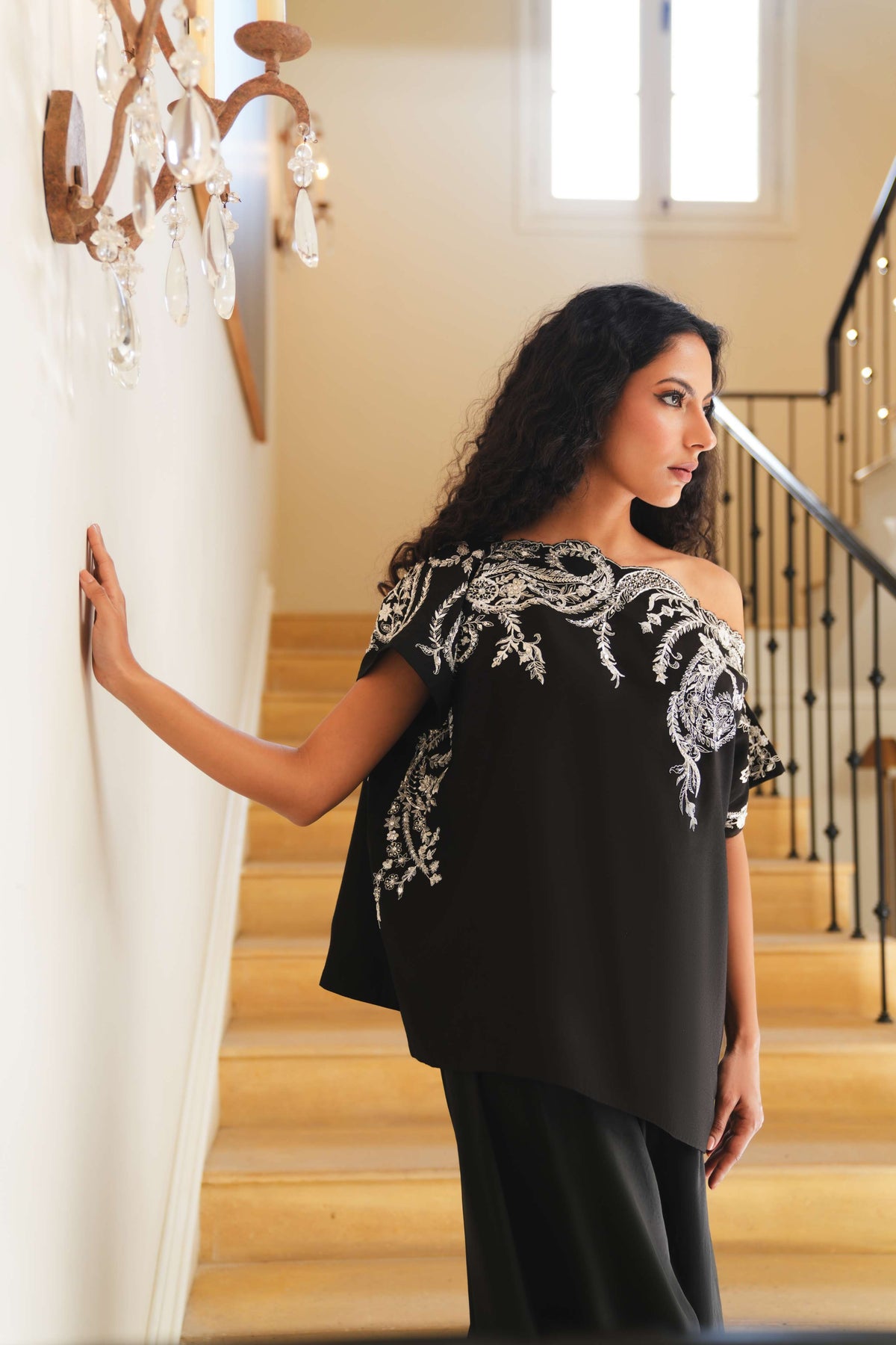 Woman in a black top with white embroidery standing on a staircase