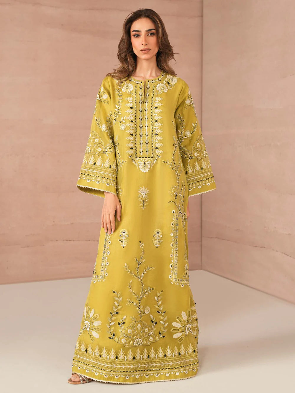 Woman wearing a yellow embroidered dress against a beige background