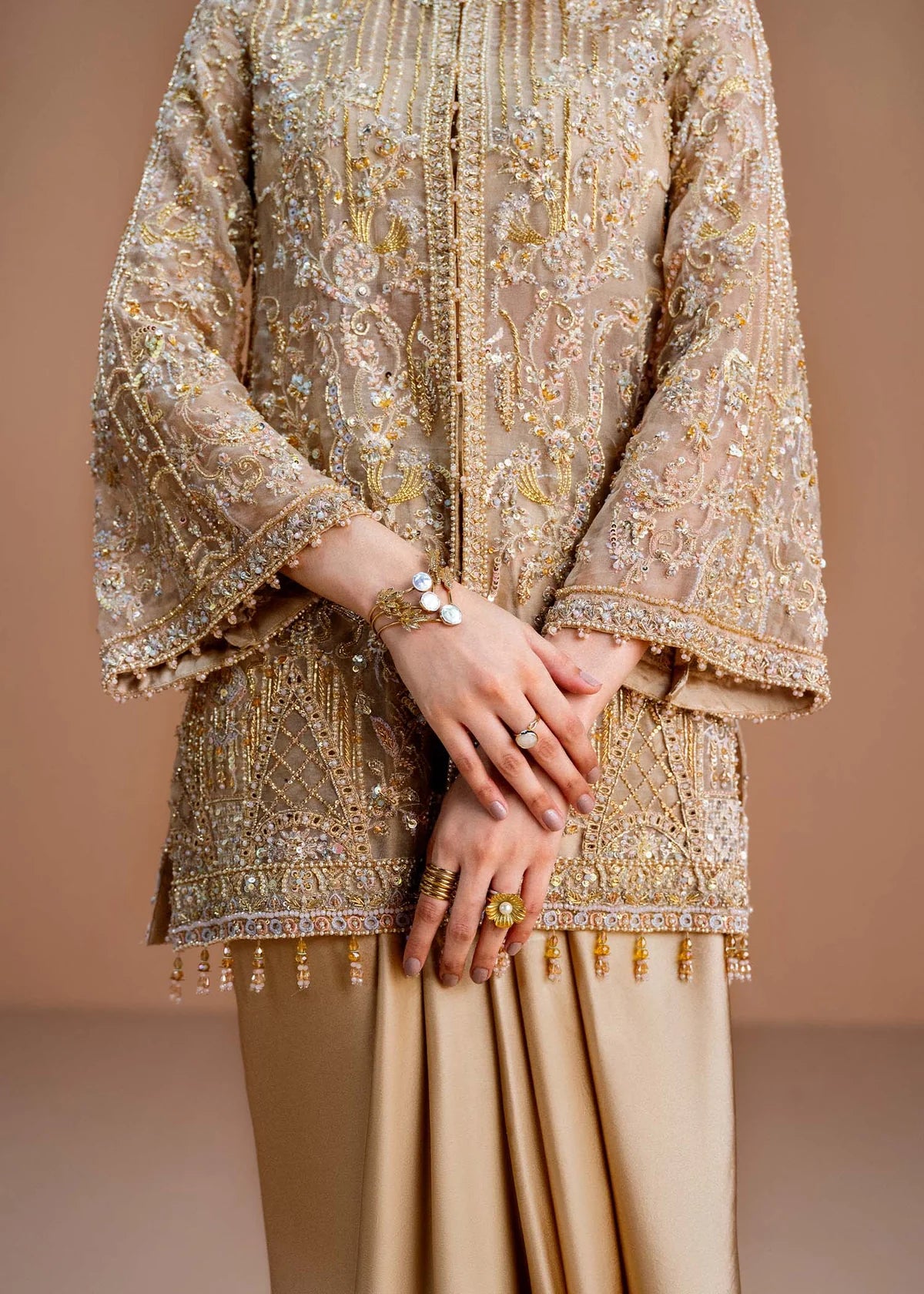 Beige embroidered traditional outfit with jewelry on a beige background