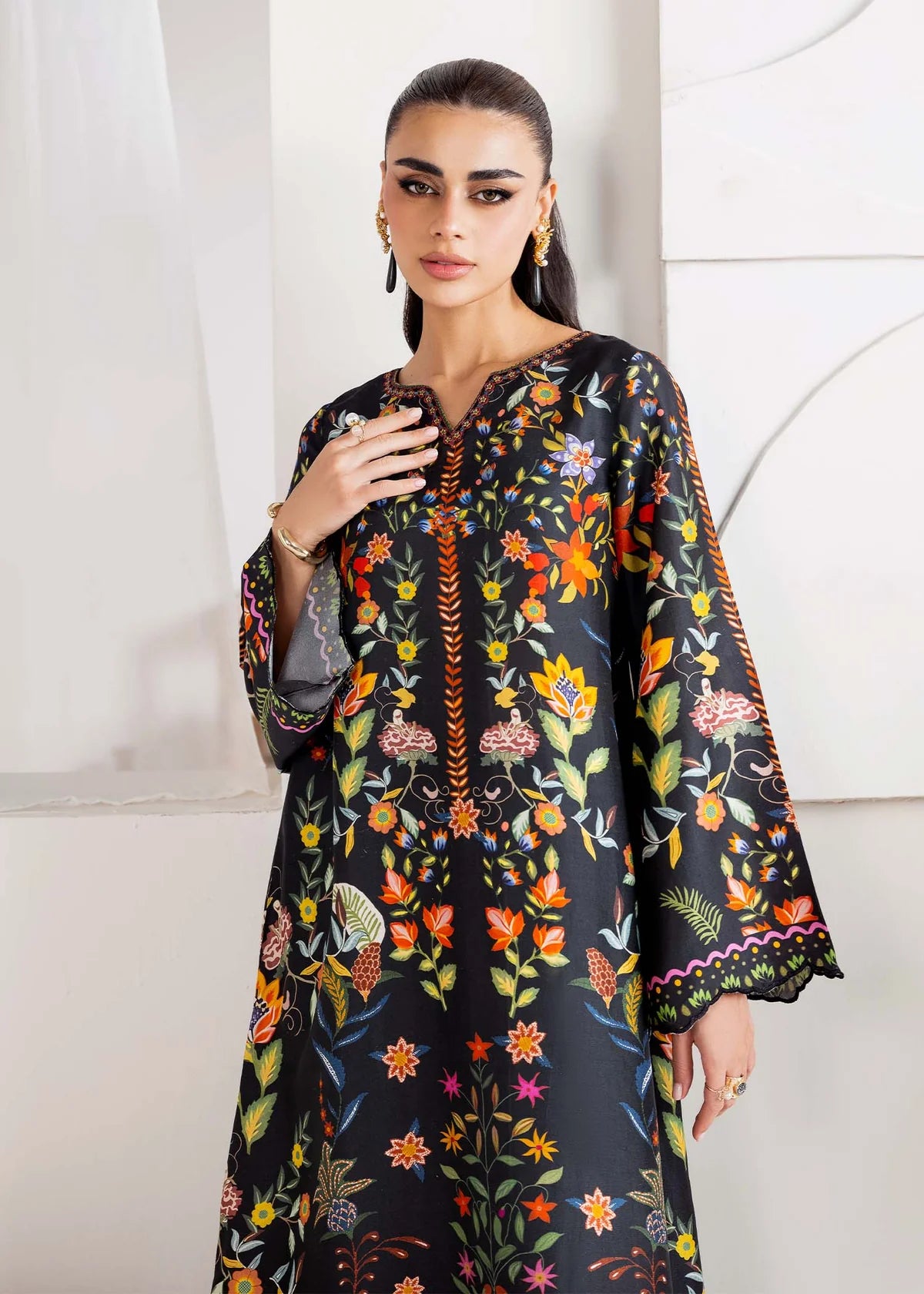 Woman wearing a black floral dress with colorful patterns against a white background