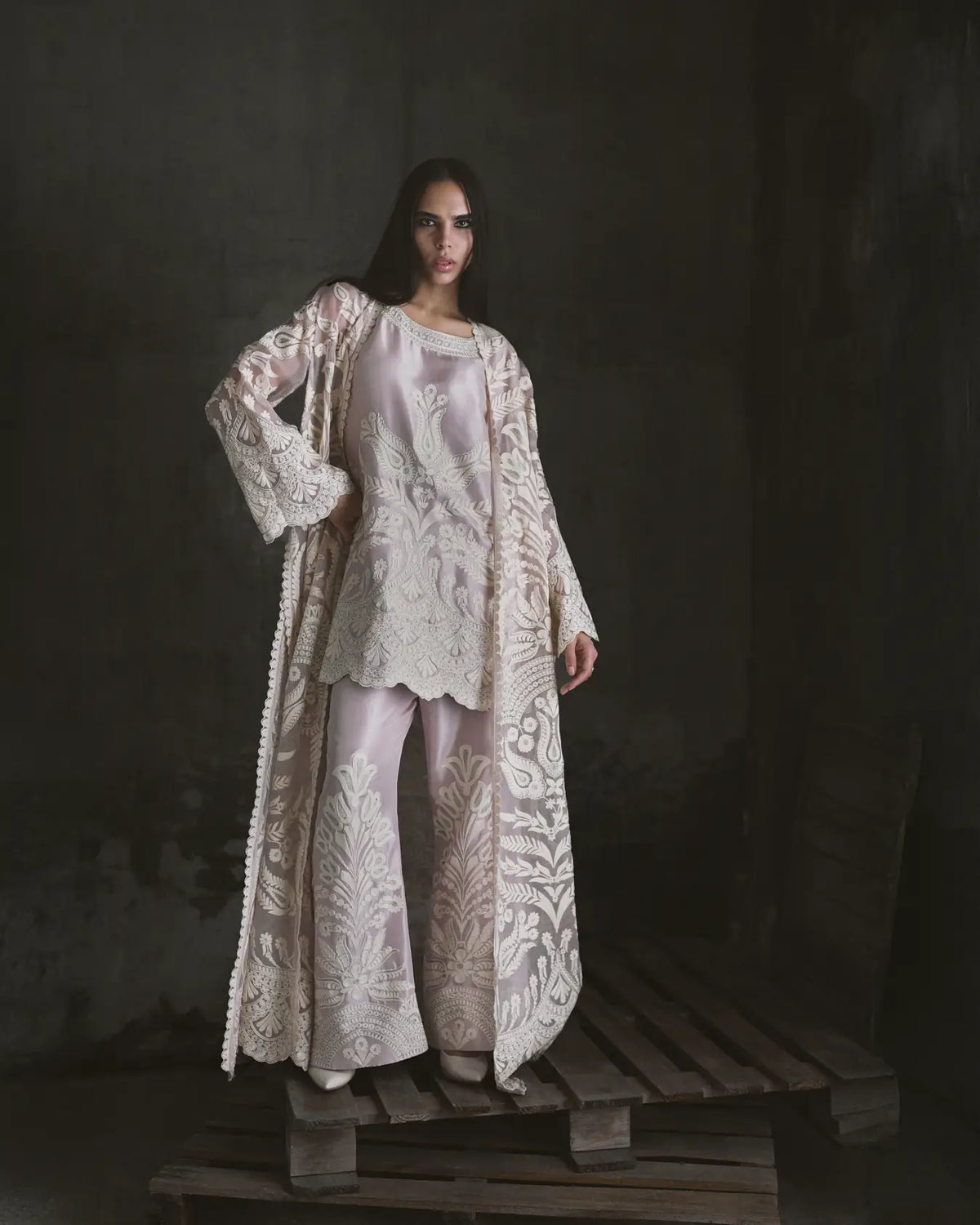 Woman wearing a detailed white outfit on a dark background