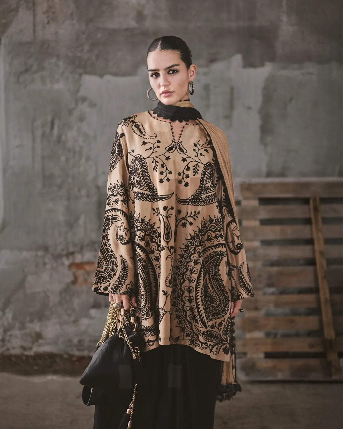 Woman wearing a patterned beige and black outfit in an industrial setting