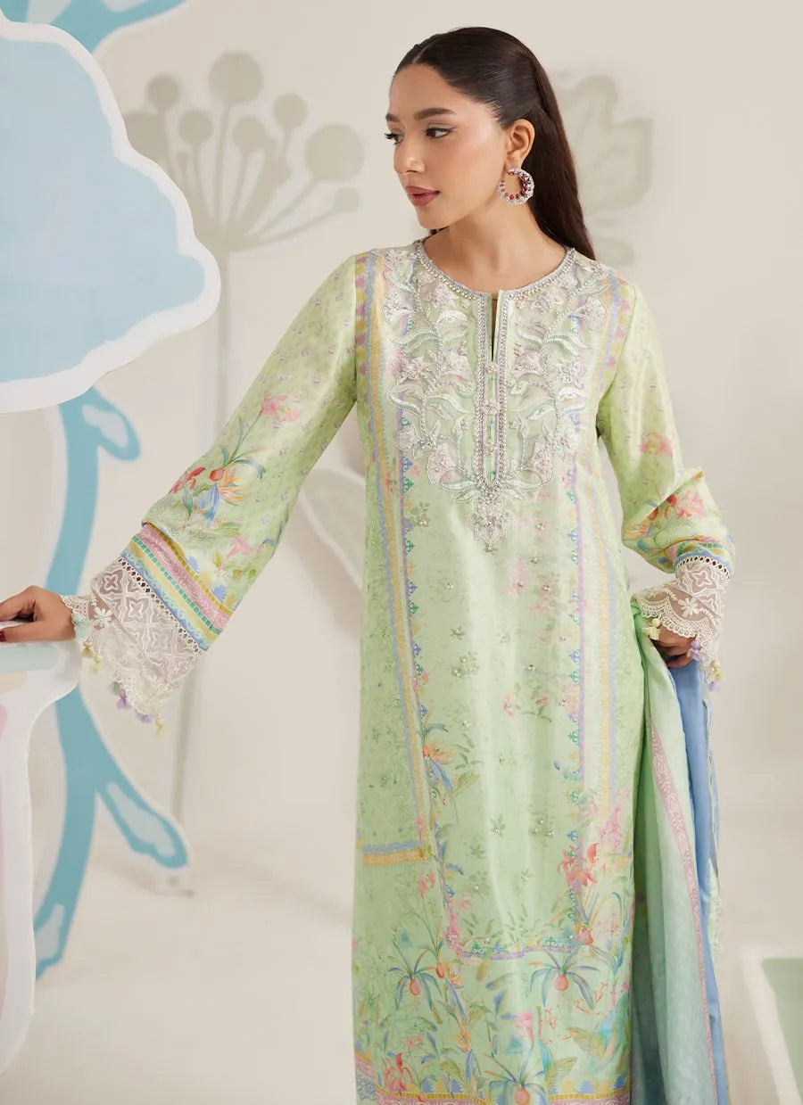 Woman wearing a light green embroidered dress with floral patterns against a white background